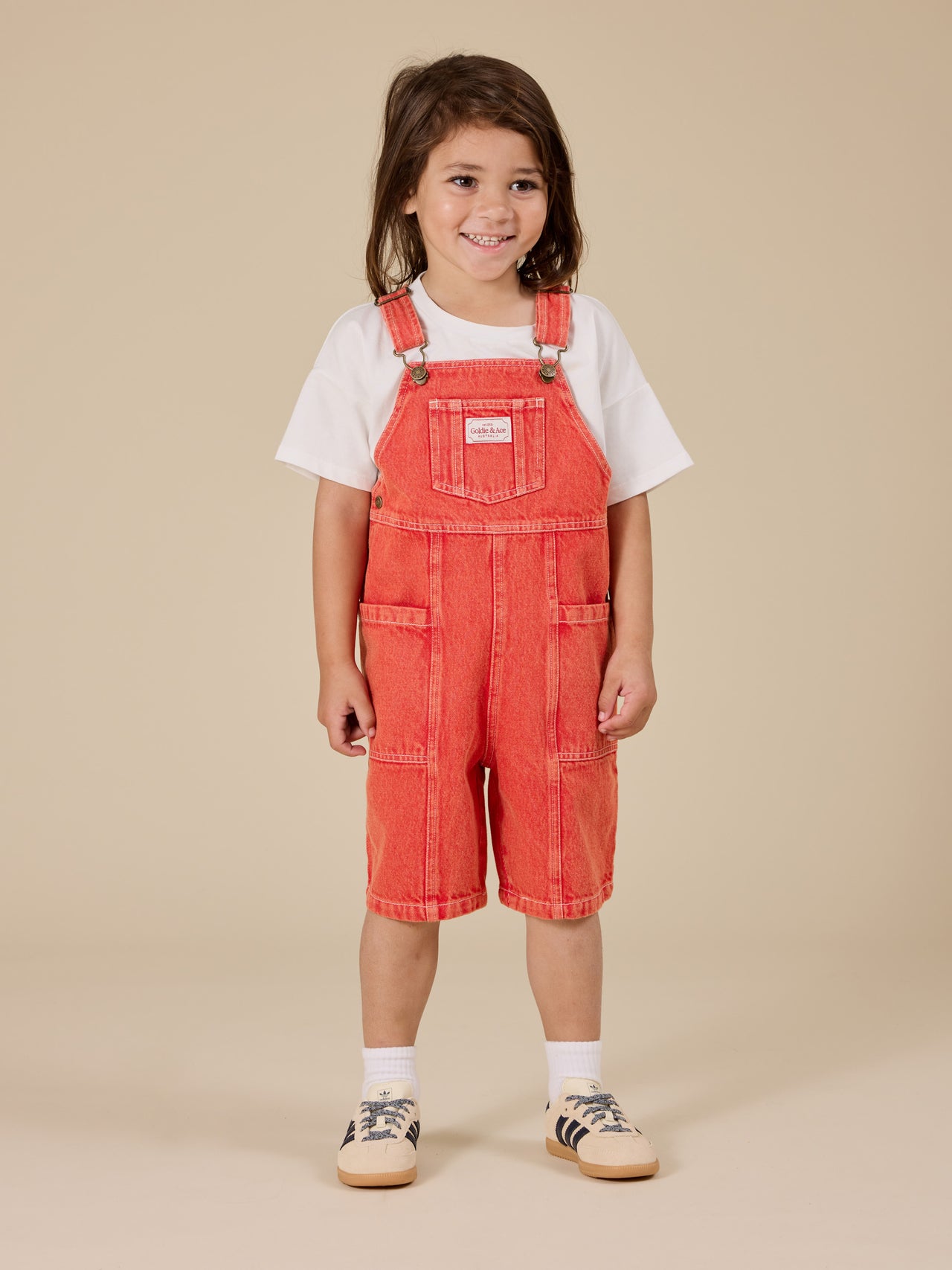 The Goldie + Ace James Vintage Washed Denim Pocket Overalls in Apple Red pictured on a transparent background. The material is 100% cotton. It is a overall made for babies, toddlers and kids.