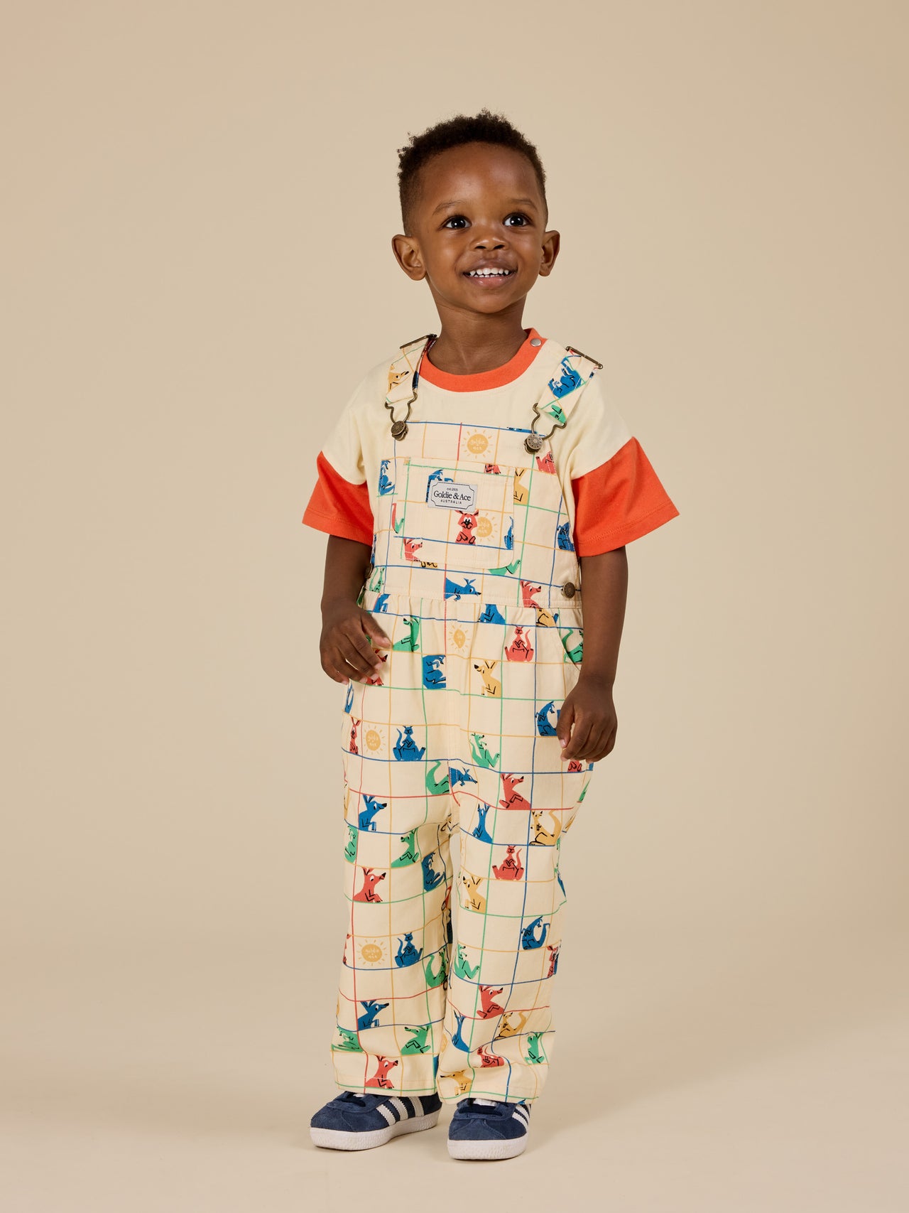 The Goldie + Ace Hopscotch Austin Denim Overalls in Vanilla/Primary pictured on a transparent background. The material is 100% cotton. It is a overall made for babies, toddlers and kids.