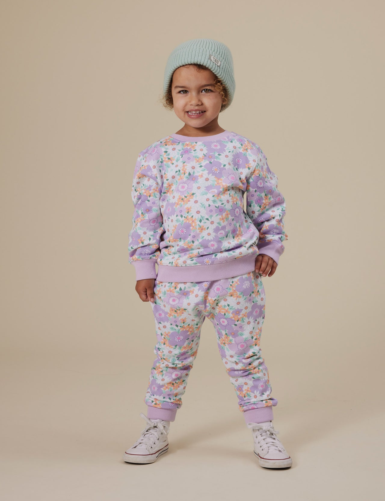 The Goldie + Ace Flora Terry Sweatpants in Lilac Multi pictured on a grey background. The material is cotton terry. It is a bottom made for babies, toddlers and kids.