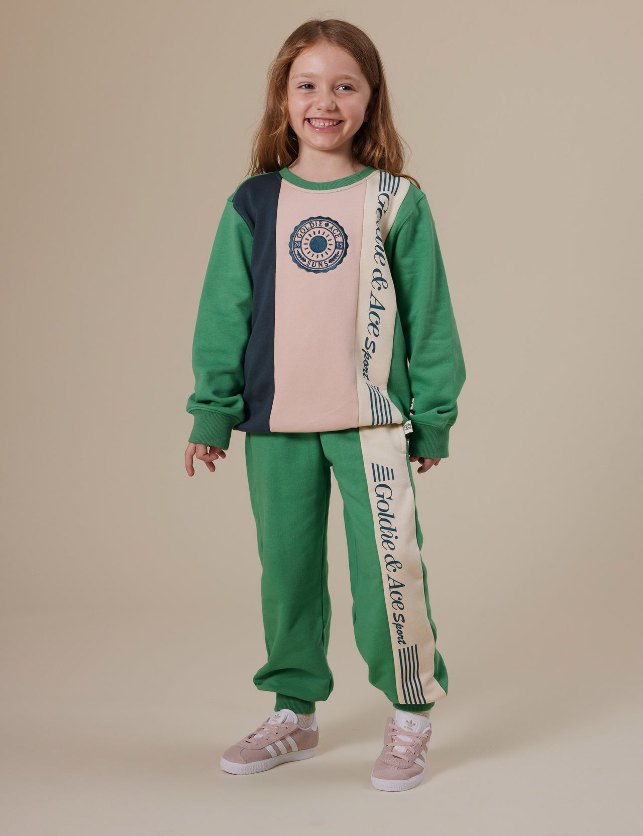 The Goldie + Ace Goldie Sports Day Trackie Pants in Green pictured on a grey background. The material is cotton terry. It is a bottom made for babies, toddlers and kids.