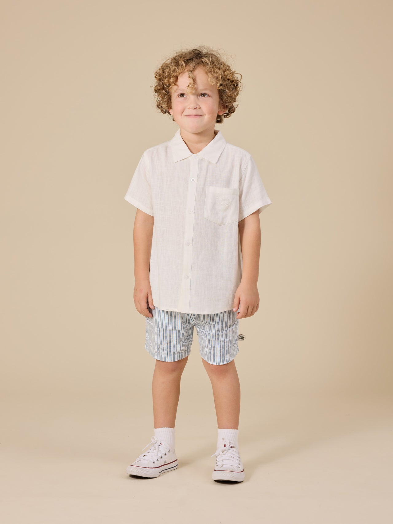 The Goldie + Ace Holiday Linen Blend Shirt in White pictured on a transparent background. The material is 100% cotton. It is a top made for babies, toddlers and kids.