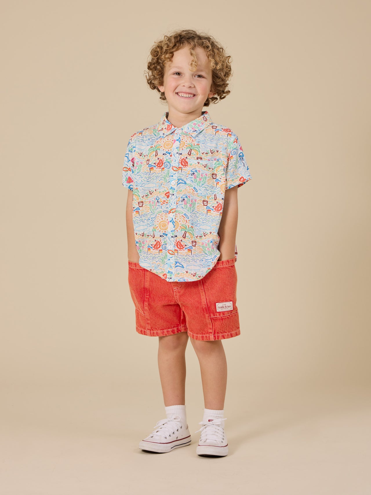 The Goldie + Ace Noah Denim Pocket Shorts in Apple Red pictured on a transparent background. The material is 100% cotton. It is a bottom made for babies, toddlers and kids.