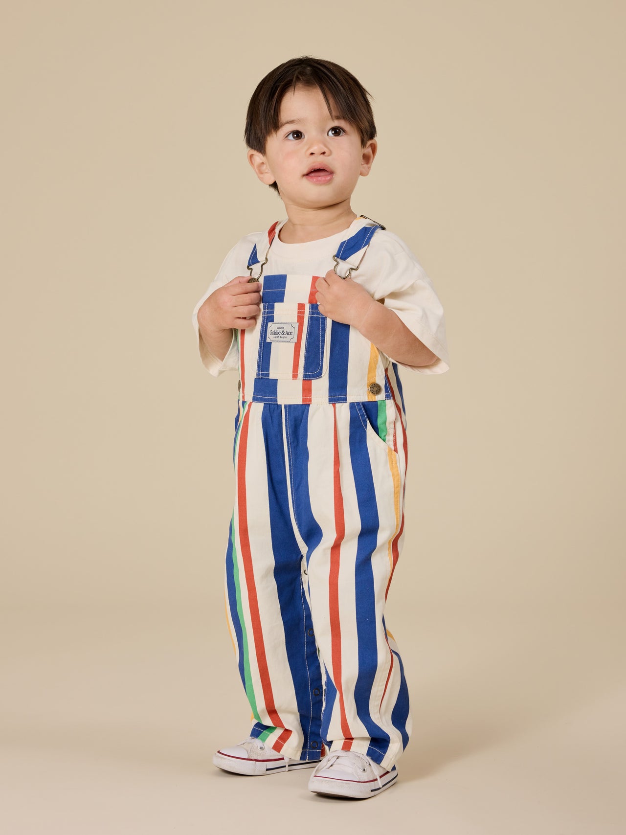 The Goldie + Ace 90's Bold Stripe Austin Denim Overalls in Primary pictured on a transparent background. The material is 100% cotton. It is a overall made for babies, toddlers and kids.