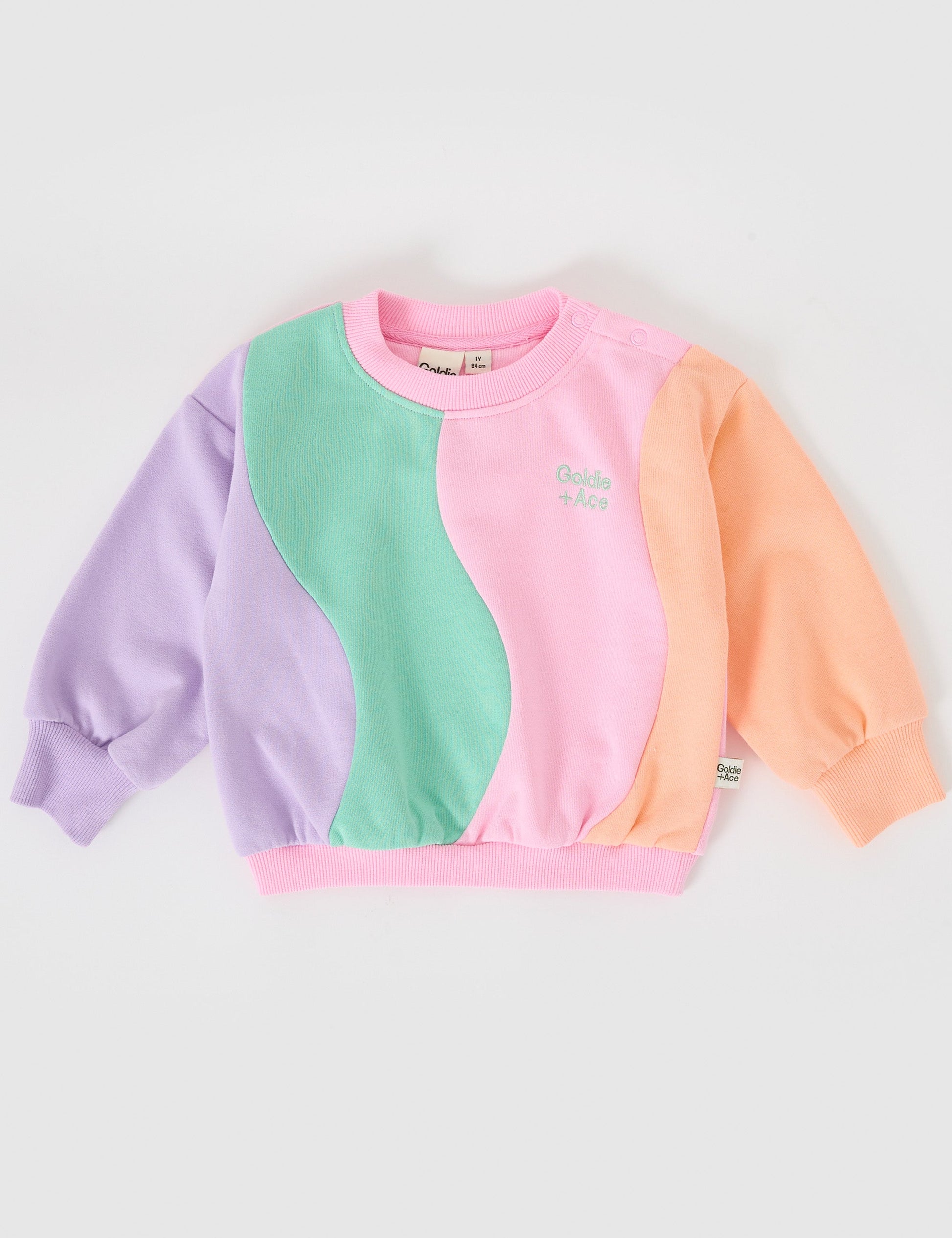 The Goldie + Ace Rio Wave Sweater Cotton Candy in Pink pictured on a grey background. The material is 100% cotton french terry. It is a top made for babies, toddlers and kids.