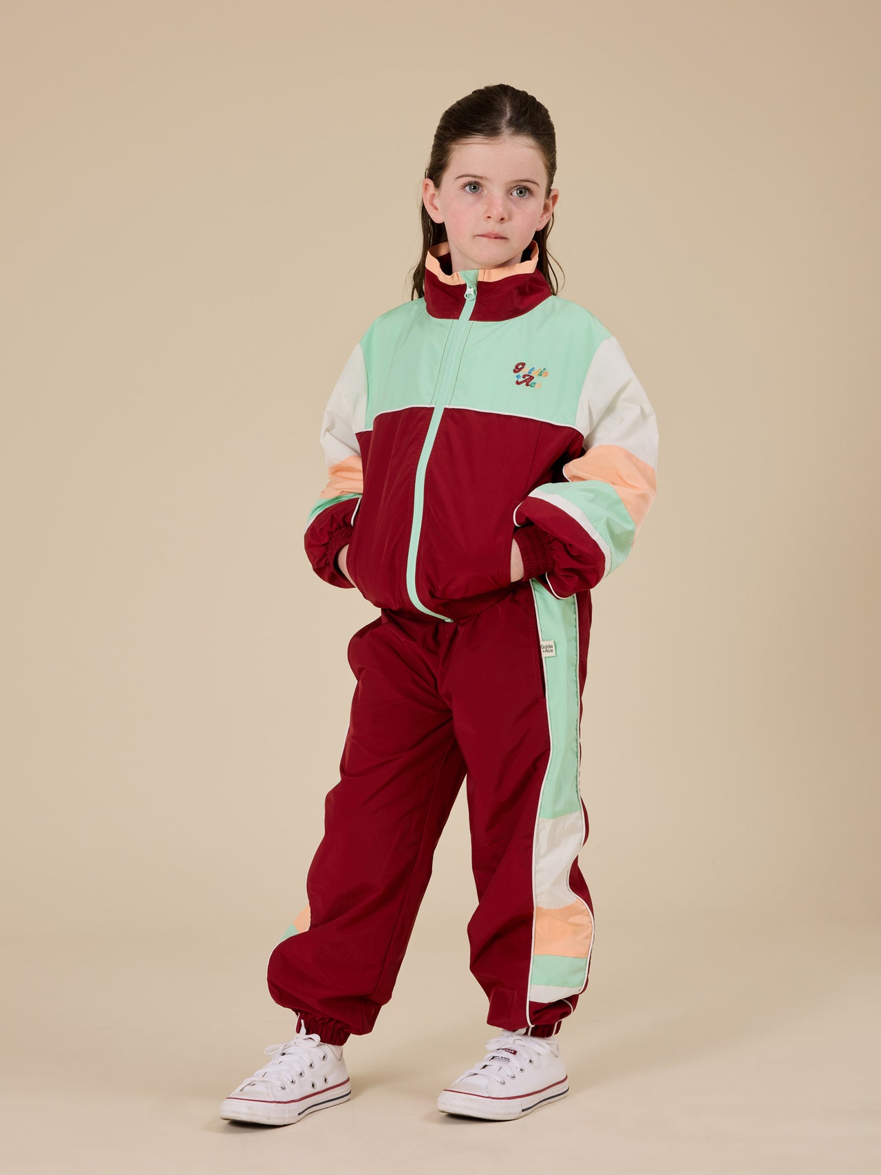 The Goldie + Ace Retro Sporty Pants in Brick/Peapod pictured on a transparent background. The material is poly with cotton lining. It is a bottom made for babies, toddlers and kids.