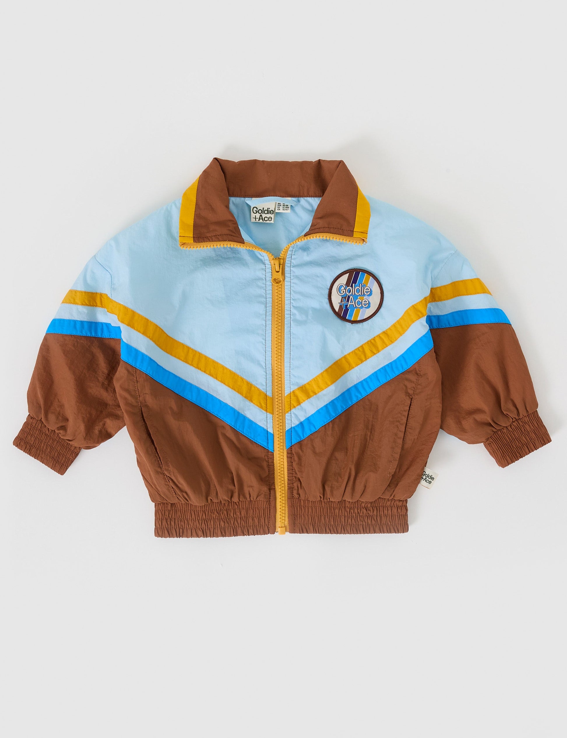 The Goldie + Ace Retro Lightweight Spray Jacket in Brown/Dusty Blue pictured on a grey background. The material is poly with poly lining. It is a jacket made for babies, toddlers and kids.