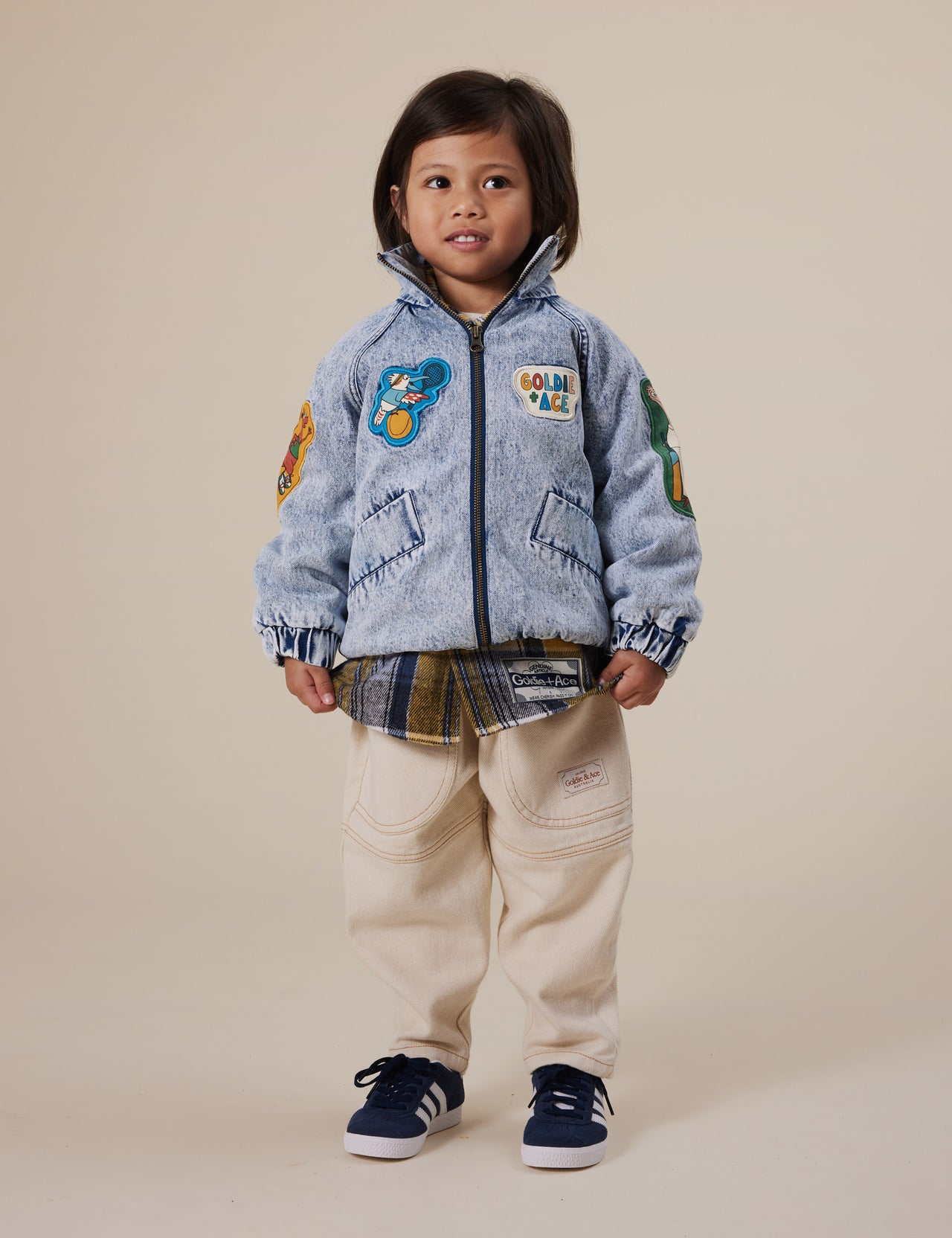 The Goldie + Ace Ari Denim Jacket in Blue Denim pictured on a grey background. The material is denim with poly sherpa lining. It is a jacket made for babies, toddlers and kids.
