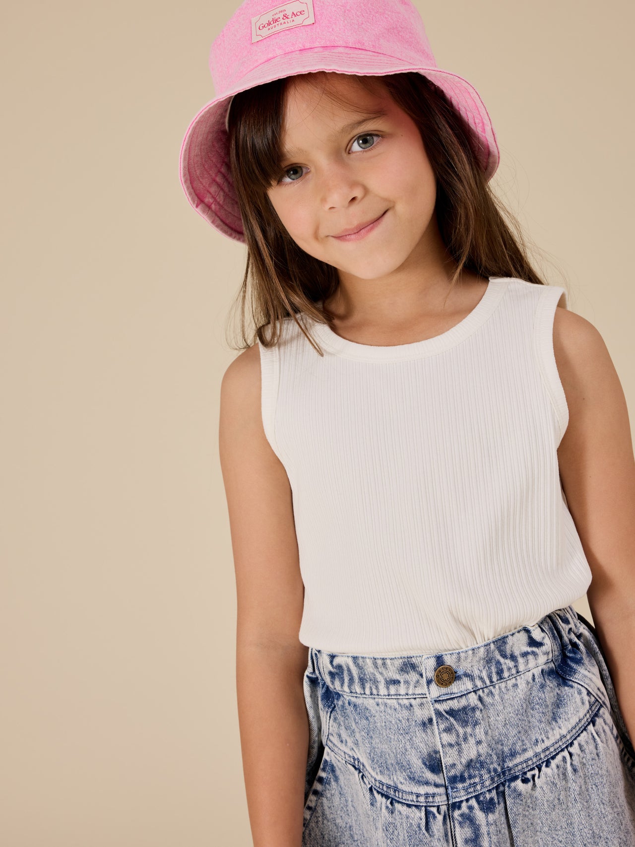 The Goldie + Ace Denim Bucket Hat in Pink Lemonade pictured on a transparent background. The material is cotton with cotton lining. It is a accessory made for babies, toddlers and kids.