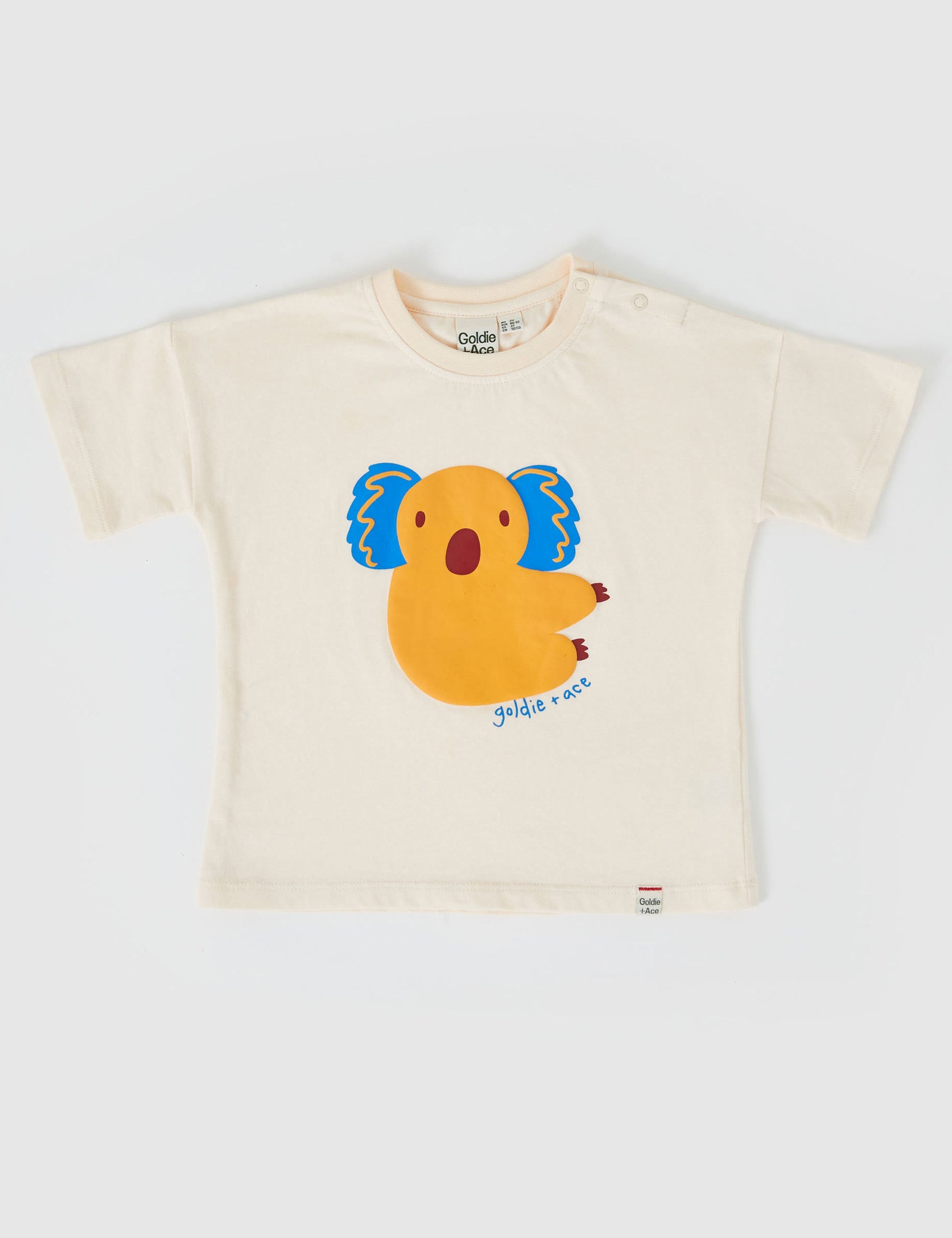 The Goldie + Ace Koala Puff Print T-Shirt in Ivory pictured on a grey background. The material is cotton jersey. It is a top made for babies, toddlers and kids.