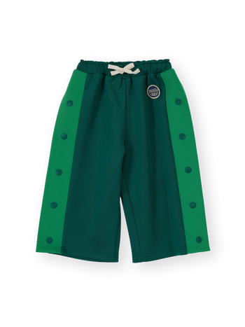 The Goldie + Ace Logo Track Snap Pants in Green pictured on a transparent background. The material is 100% polyester. It is a sweatpant made for babies, toddlers and kids.