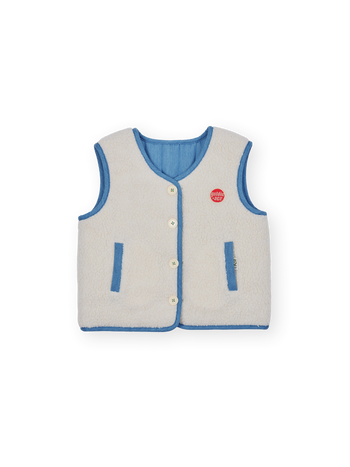 The Goldie + Ace Reversible Chambray Button Vest in Natural & Vintage Blue pictured on a transparent background. The material is 100% cotton, 100% polyester reverse side. It is a vest made for babies, toddlers and kids.