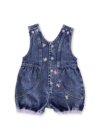 The Goldie + Ace Nina Pastel Petals Denim Romper in Dark Denim pictured on a transparent background. The material is 100% cotton. It is a romper made for babies, toddlers and kids.