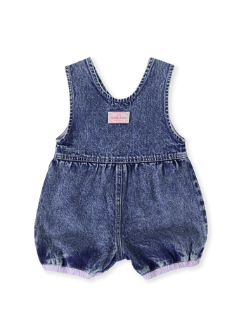 The Goldie + Ace Nina Pastel Petals Denim Romper in Dark Denim pictured on a transparent background. The material is 100% cotton. It is a romper made for babies, toddlers and kids.