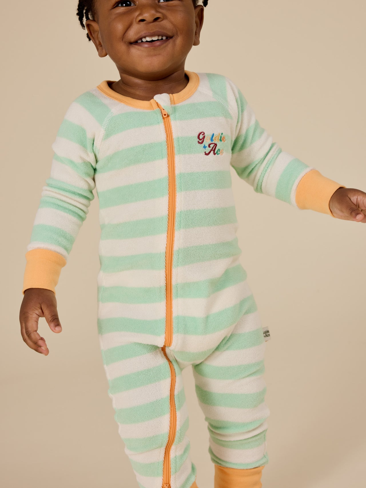 The Goldie + Ace Peas In A Pod Stripe Zipsuit in Peapod/Cloud pictured on a transparent background. The material is 100% cotton. It is a zipsuit made for babies, toddlers and kids.