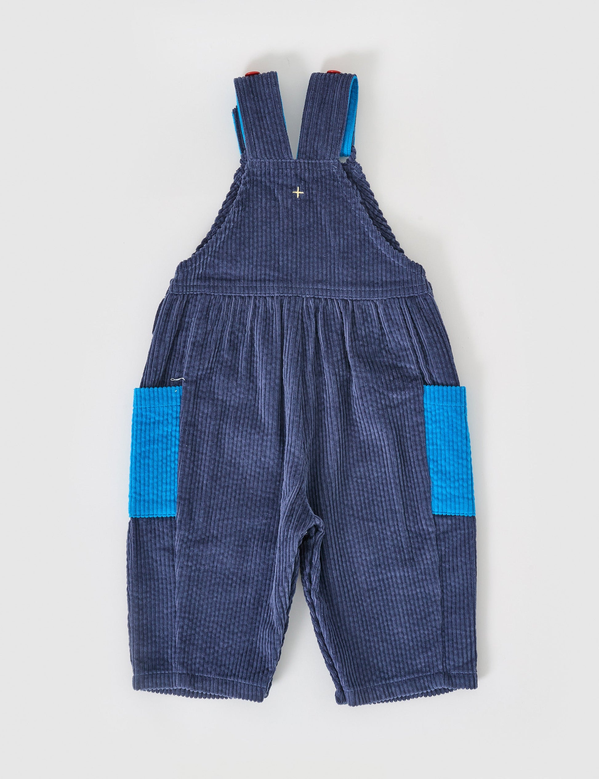 The Goldie + Ace Sammy Corduroy Colour Block Overalls in Blue/Red pictured on a grey background. The material is cotton denim. It is a overall made for babies, toddlers and kids.