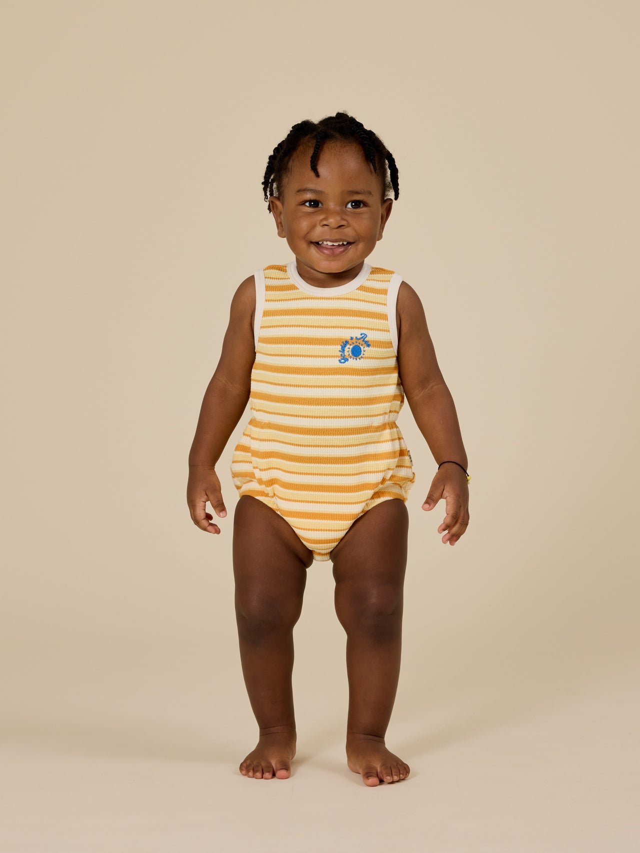 The Goldie + Ace Sunshine Stripe Bubble Romper in Lemon/Golden pictured on a transparent background. The material is 100% cotton. It is a romper made for babies, toddlers and kids.