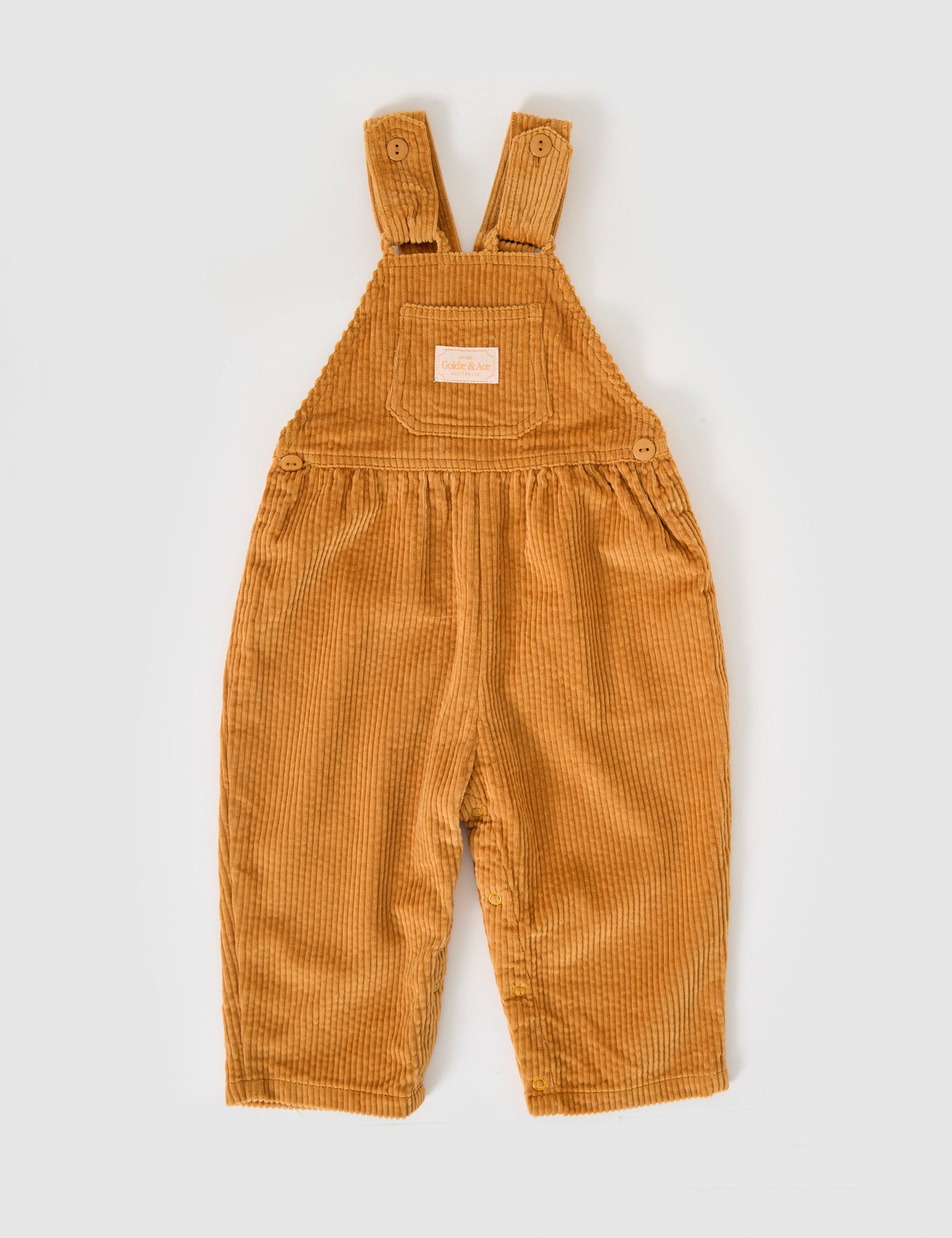 The Goldie + Ace Sammy Corduroy Overalls in Golden pictured on a grey background. The material is cotton cord. It is a overall made for babies, toddlers and kids.