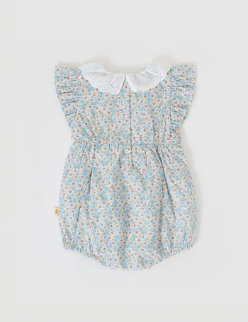 The Goldie + Ace Sunny Floral Lani Smocked Romper in Sunny Floral pictured on a grey background. The material is cotton. It is a babywear made for babies, toddlers and kids.