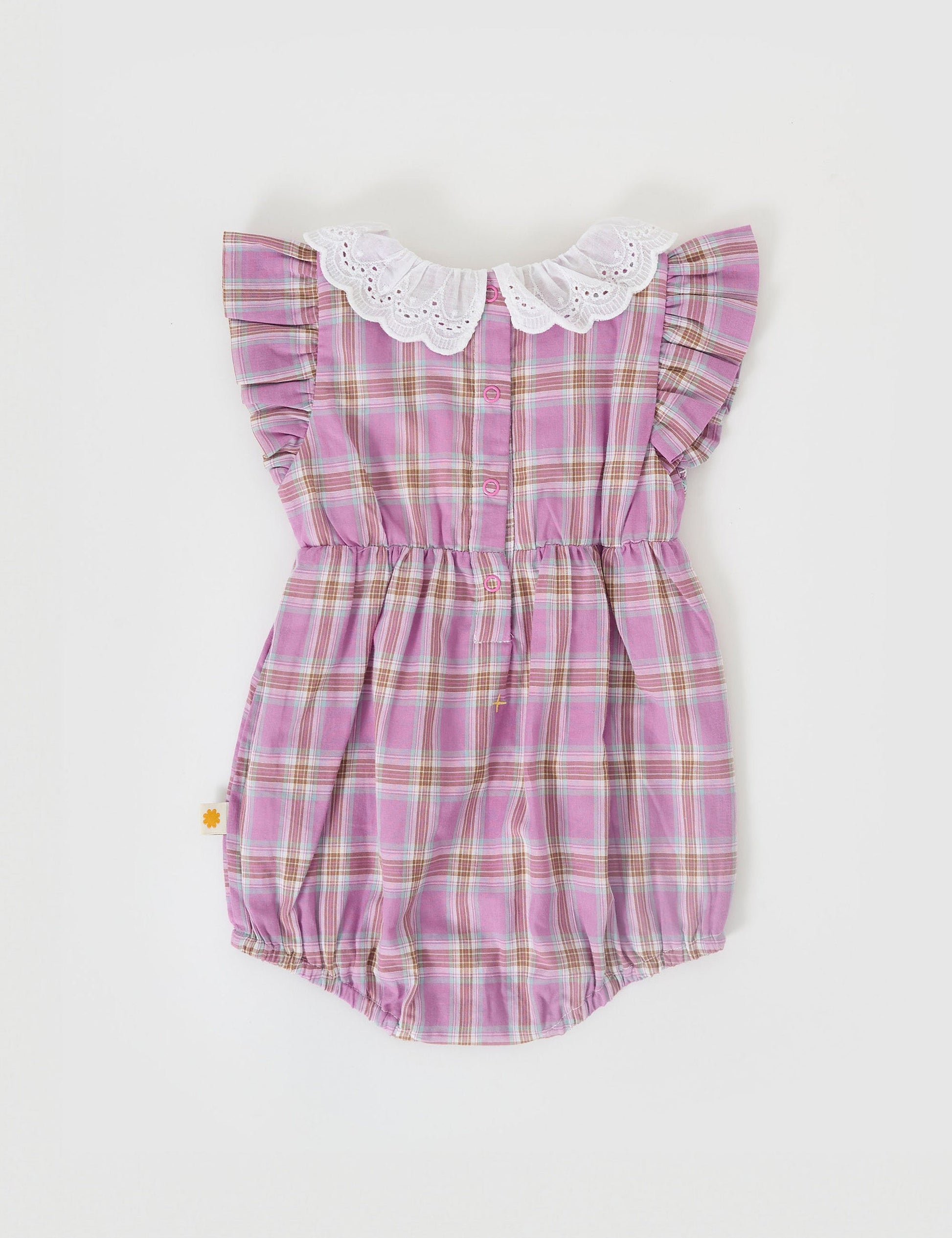 The Goldie + Ace Mauve Check Lani Smocked Romper in Mauve Check pictured on a grey background. The material is cotton. It is a babywear made for babies, toddlers and kids.