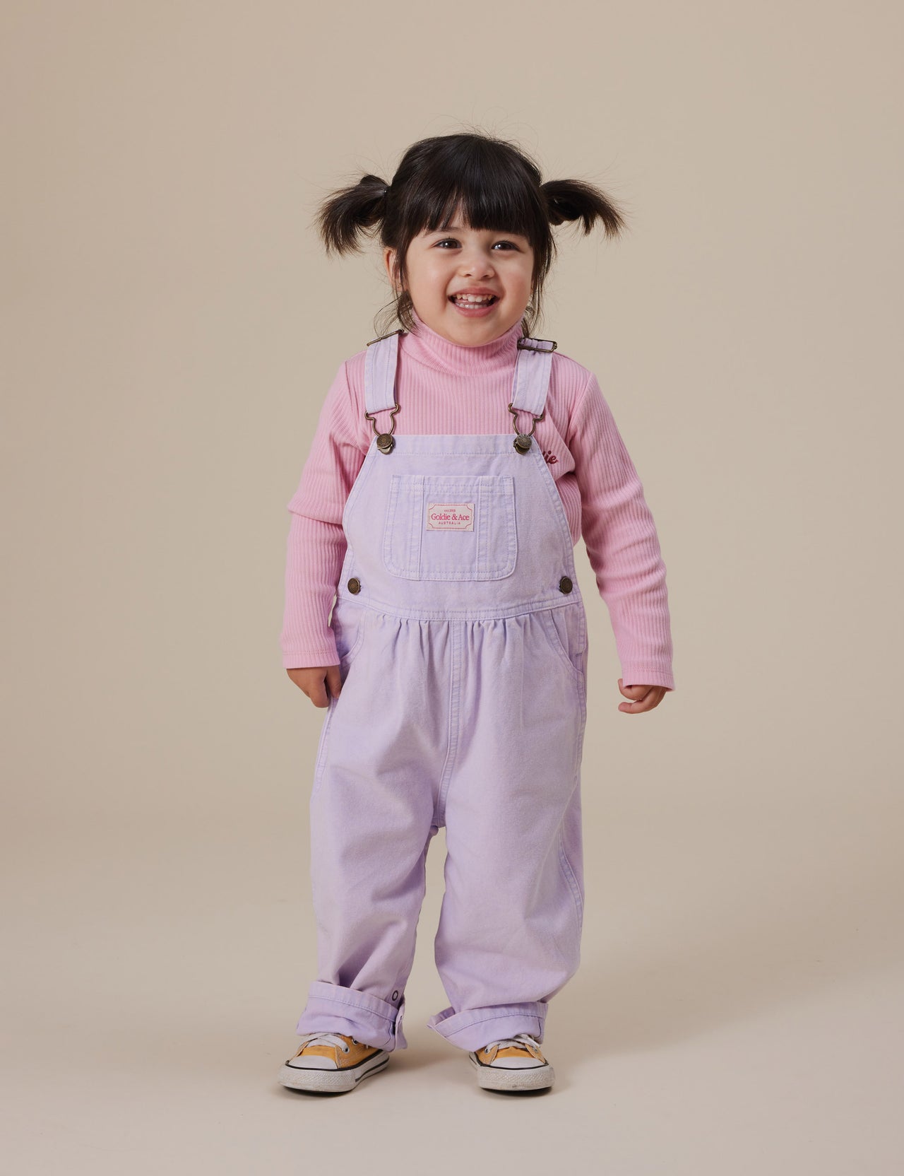 The Goldie + Ace Austin Vintage Washed Denim Overalls in Mauve pictured on a grey background. The material is cotton denim. It is a overall made for babies, toddlers and kids.