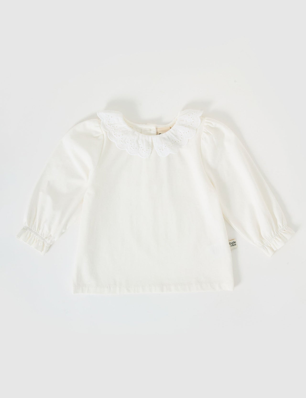 The Goldie + Ace Laura Puff Sleeve Collar Long Sleeve in White pictured on a grey background. The material is cotton jersey. It is a top made for babies, toddlers and kids.