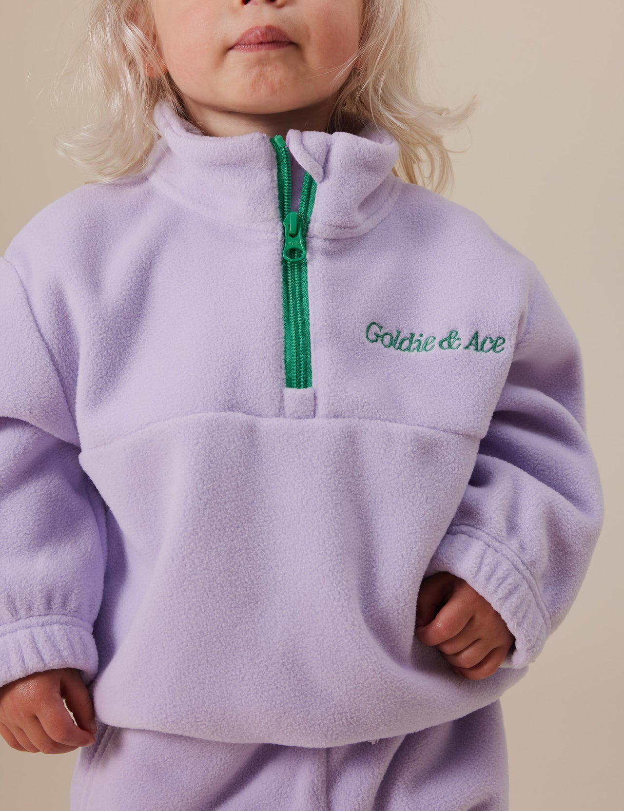 The Goldie + Ace Bobbi Polar Fleece Sweater in Lilac pictured on a grey background. The material is polyester. It is a top made for babies, toddlers and kids.