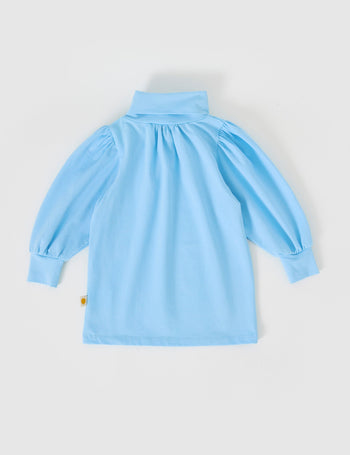 The Goldie + Ace Sofia Embroidered Puff Sleeve Skivvy in Sky Blue pictured on a grey background. The material is cotton jersey. It is a top made for babies, toddlers and kids.