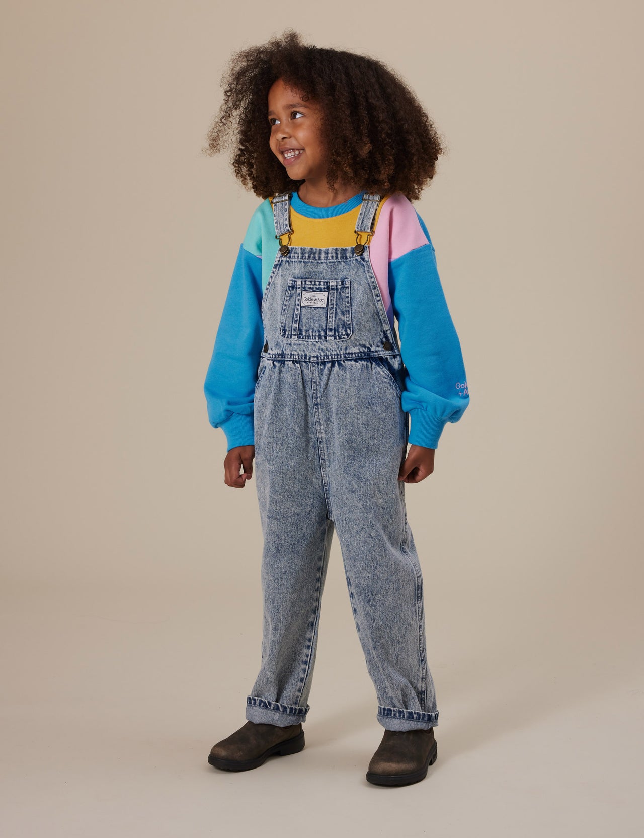 The Goldie + Ace Austin Vintage Washed Denim Overalls in Light Denim pictured on a grey background. The material is cotton denim. It is a overall made for babies, toddlers and kids.