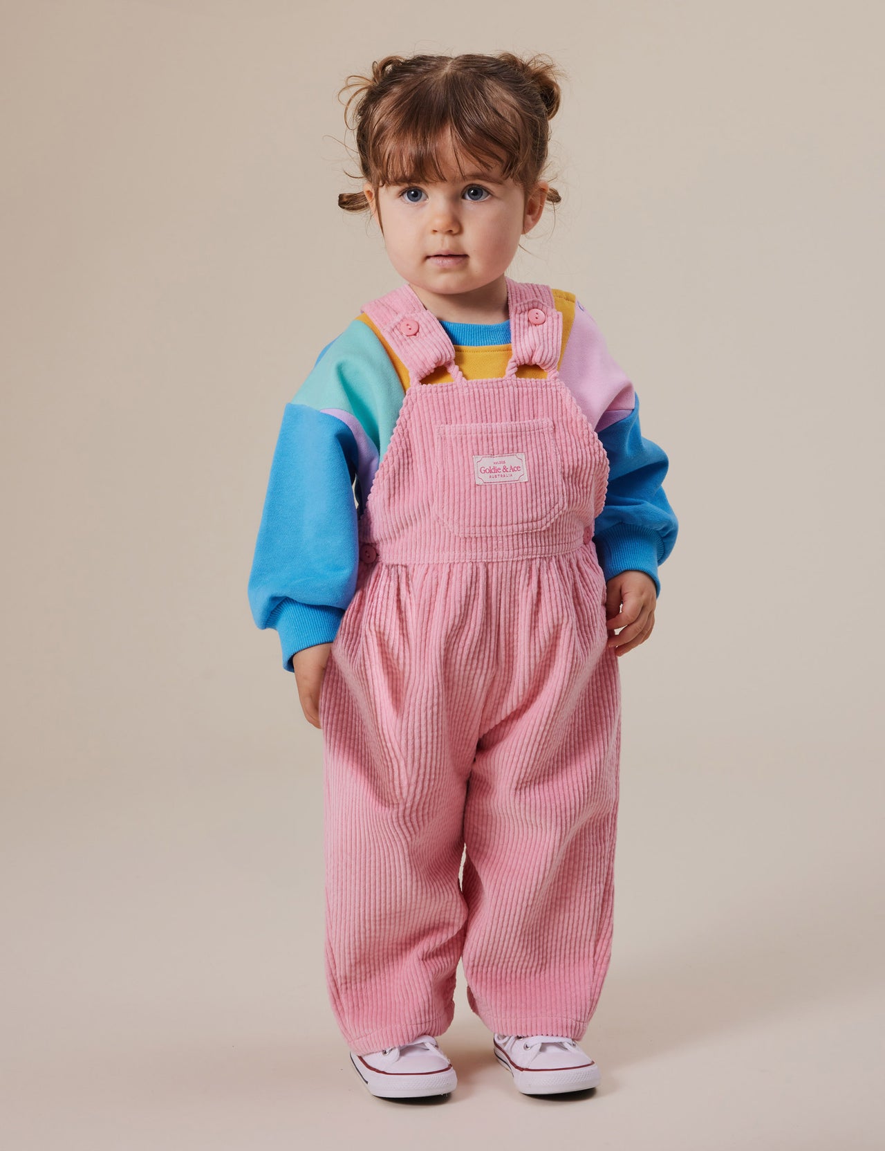 The Goldie + Ace Sammy Corduroy Overalls in Sweetpea pictured on a grey background. The material is cotton cord. It is a overall made for babies, toddlers and kids.