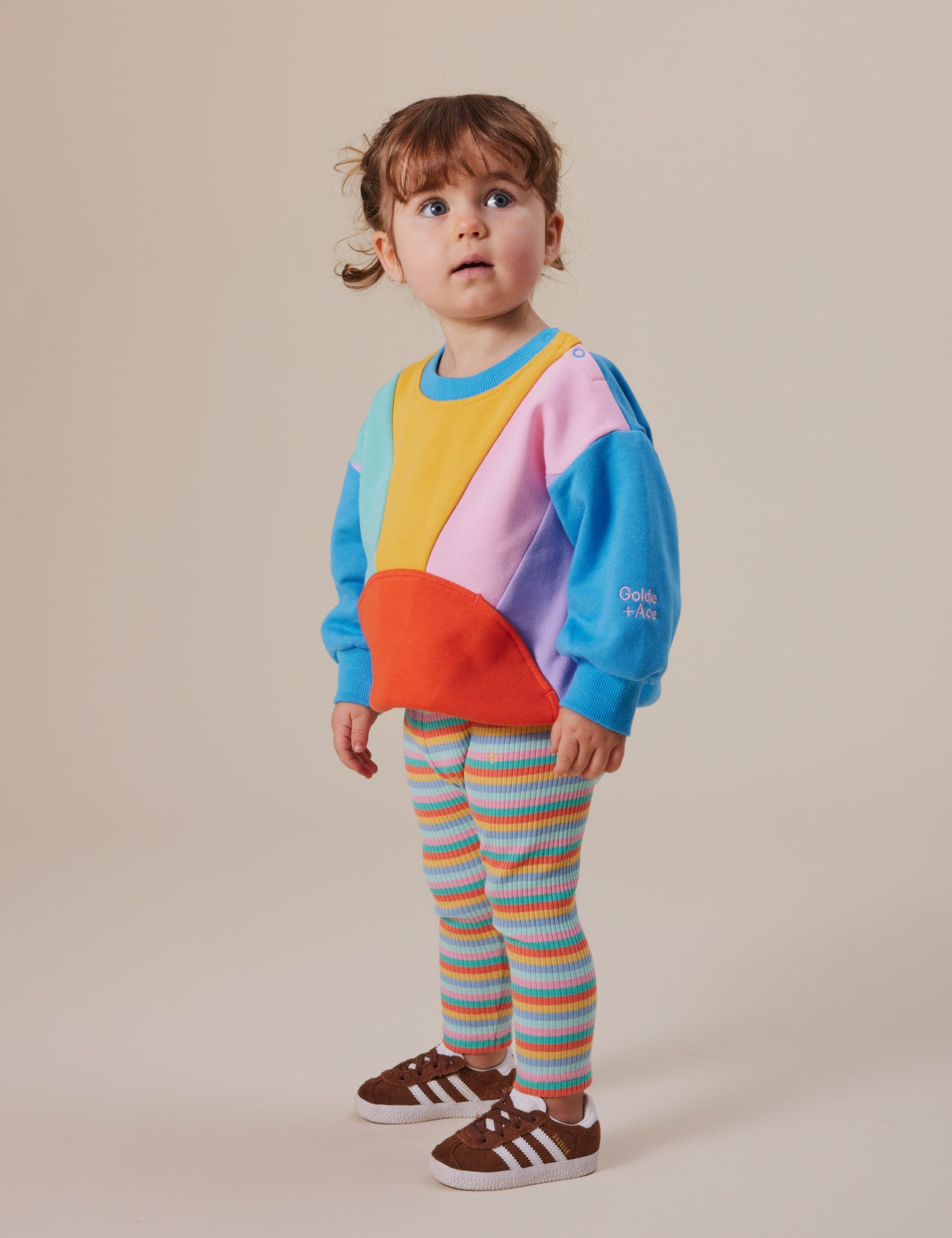 The Goldie + Ace Rib Leggings in Candy Stripe pictured on a grey background. The material is soft ribbed cotton elastane. It is a bottom made for babies, toddlers and kids.