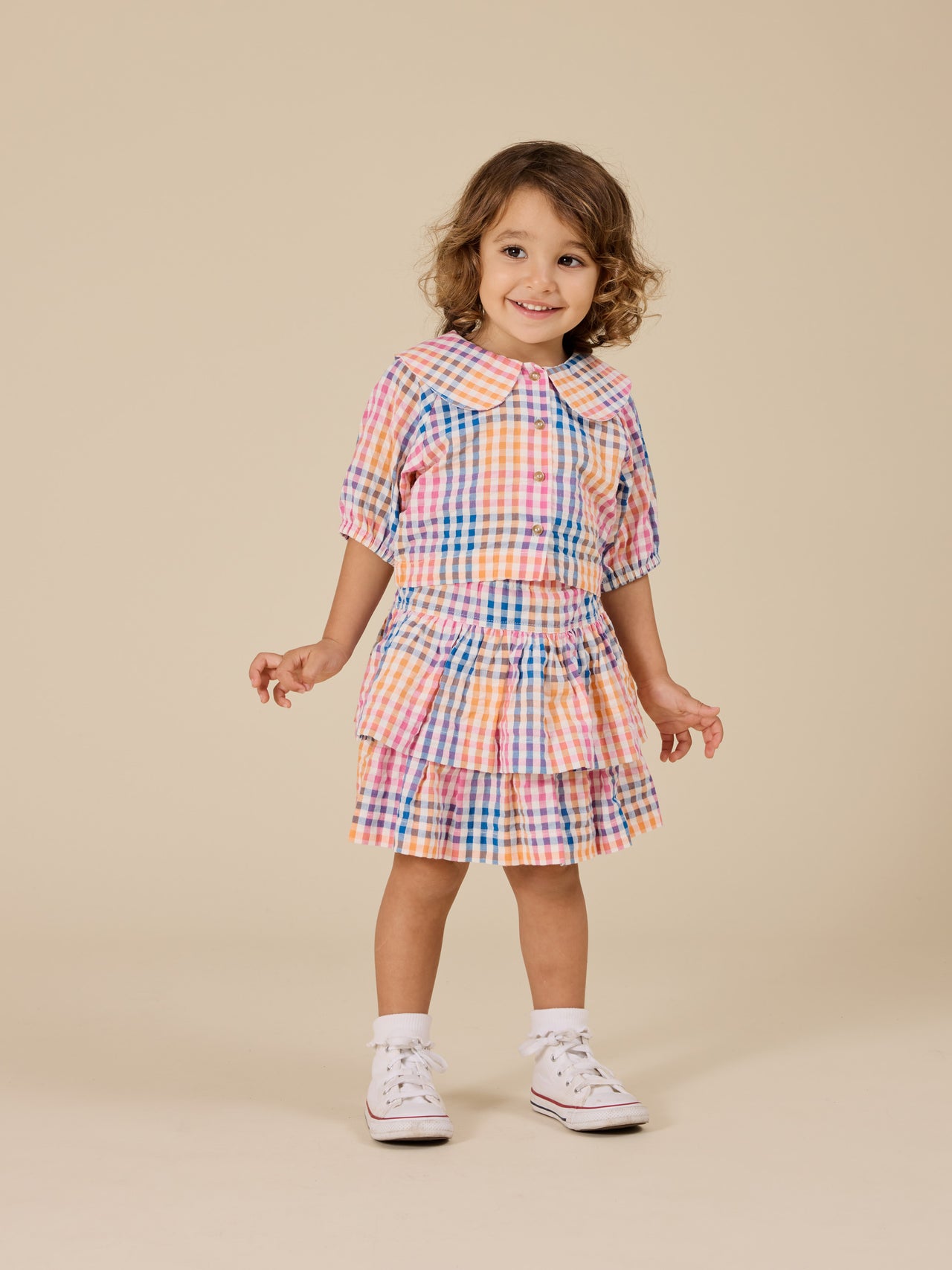 The Goldie + Ace Rainbow Gingham Ria Ruffle Skirt in Multi pictured on a transparent background. The material is 100% cotton. It is a bottom made for babies, toddlers and kids.