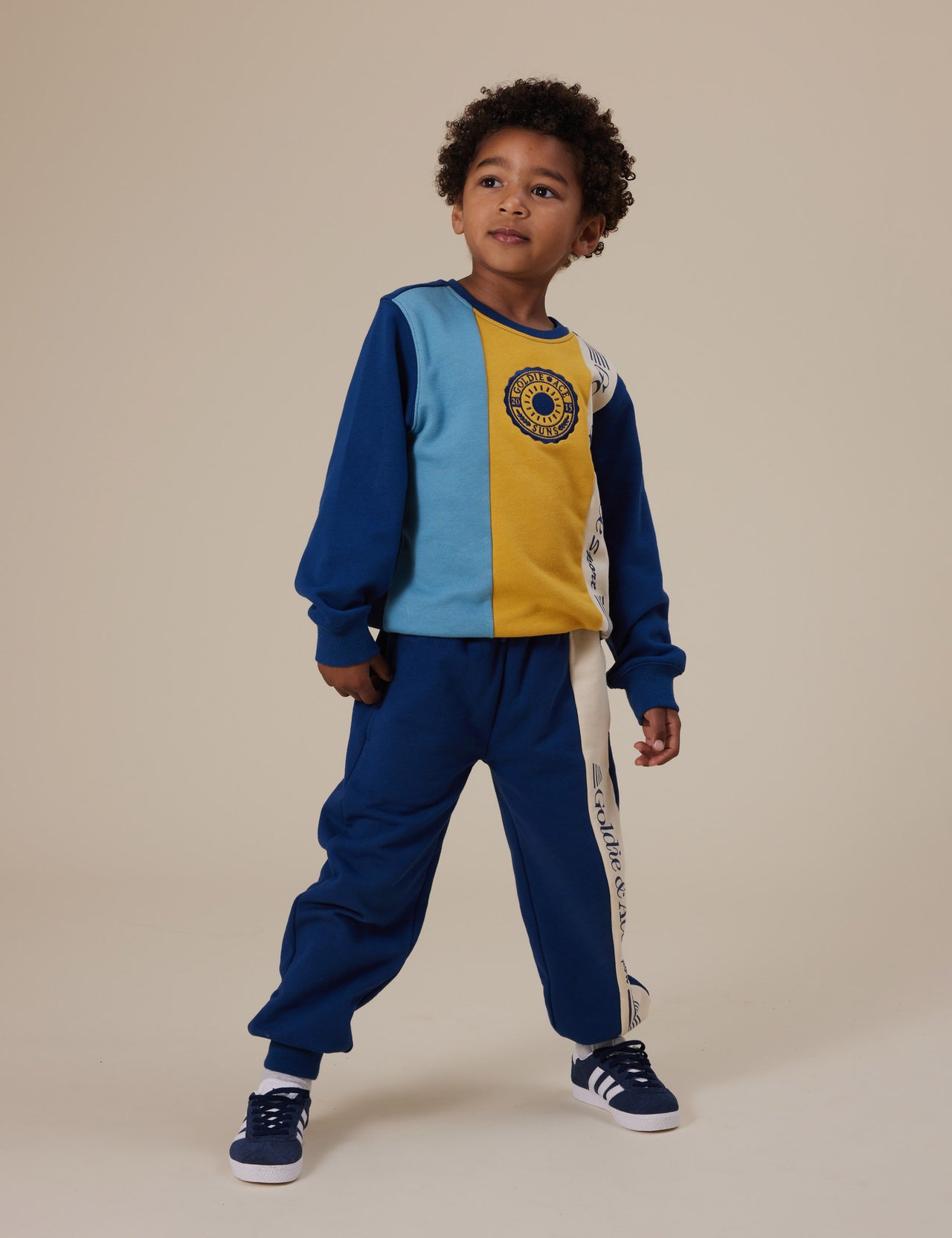 The Goldie + Ace Goldie Sports Day Trackie Pants in Navy pictured on a grey background. The material is cotton terry. It is a bottom made for babies, toddlers and kids.