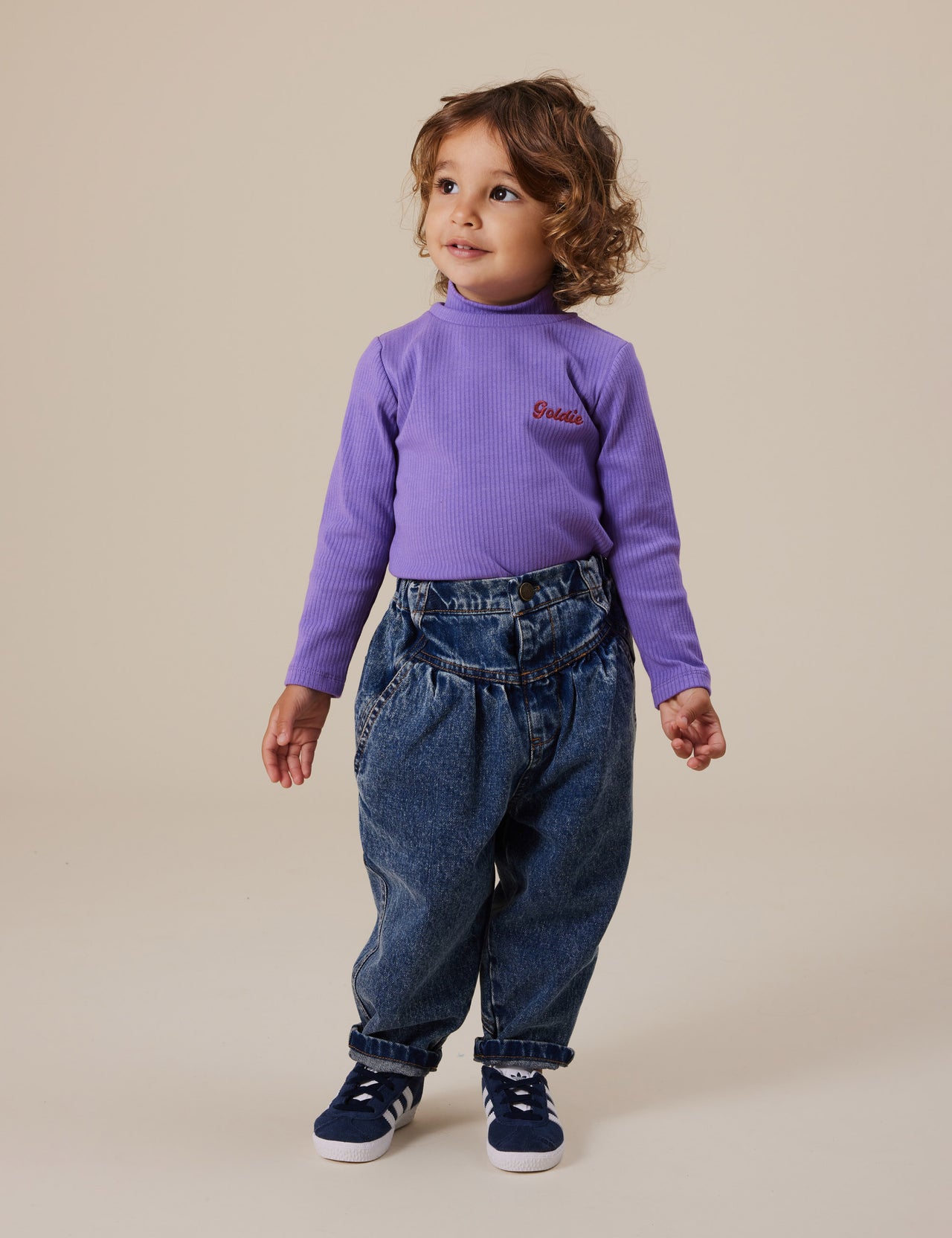 The Goldie + Ace Embroidered Rib Skivvy Grape in Grape pictured on a grey background. The material is soft ribbed cotton elastane. It is a top made for babies, toddlers and kids.