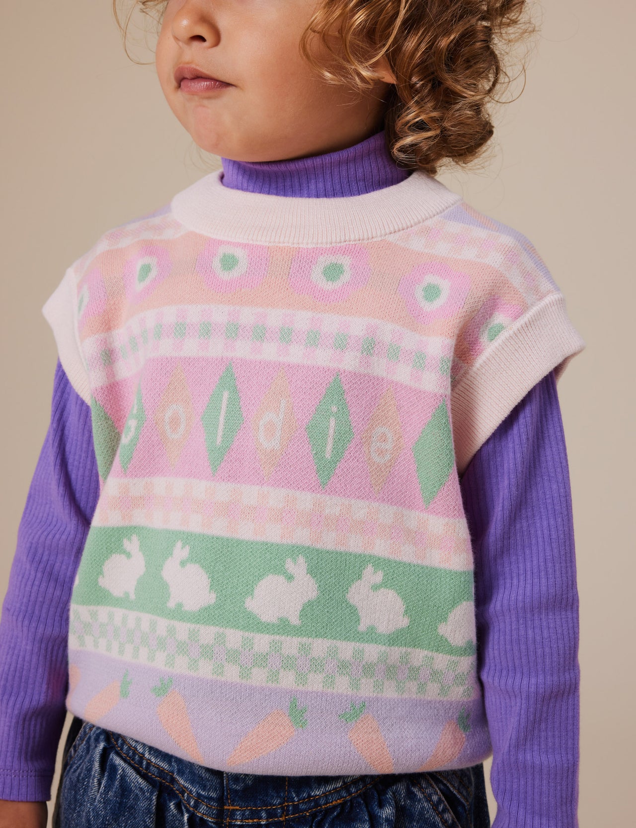 The Goldie + Ace Amy Knit Vest in Light Pastel pictured on a grey background. The material is super soft wool blend. It is a knit made for babies, toddlers and kids.