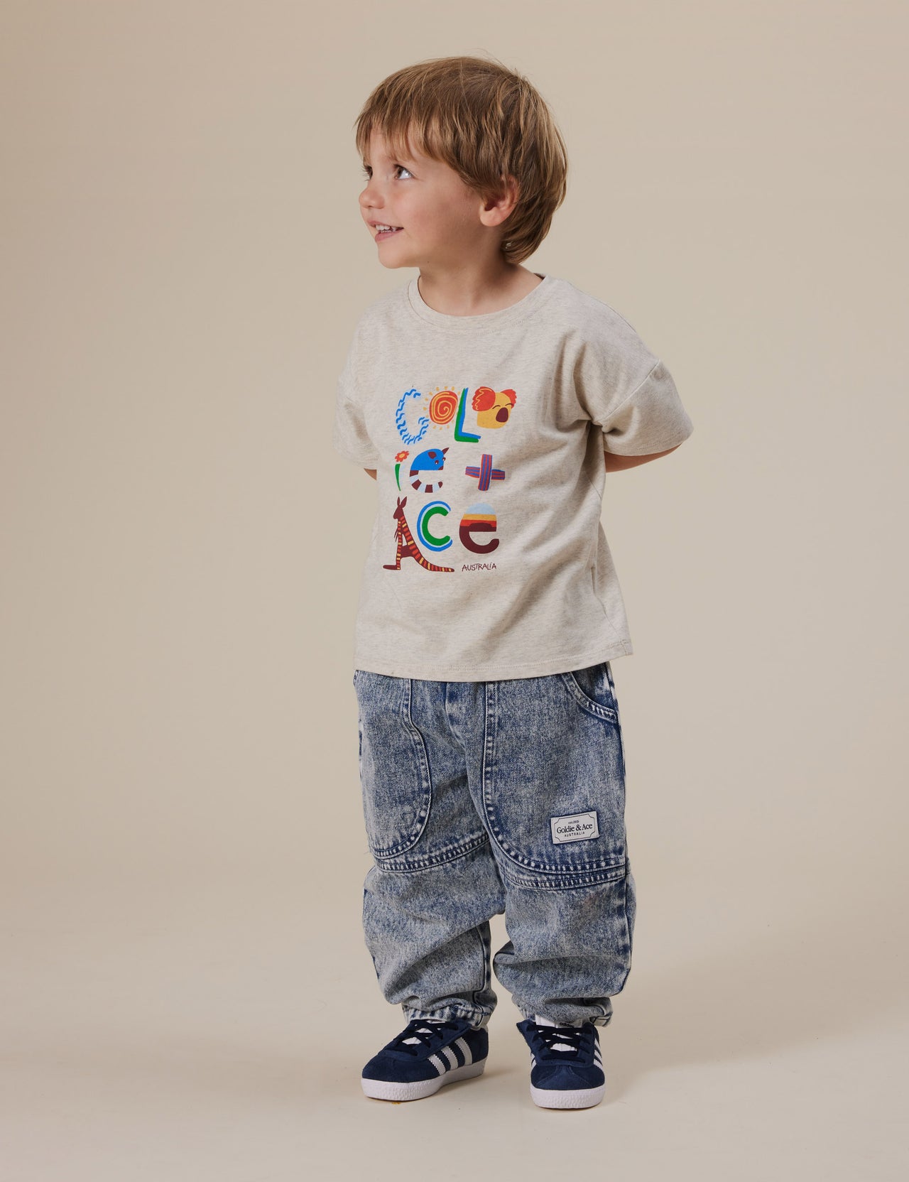 The Goldie + Ace Land Down Under T-Shirt in Marle pictured on a grey background. The material is cotton jersey. It is a top made for babies, toddlers and kids.