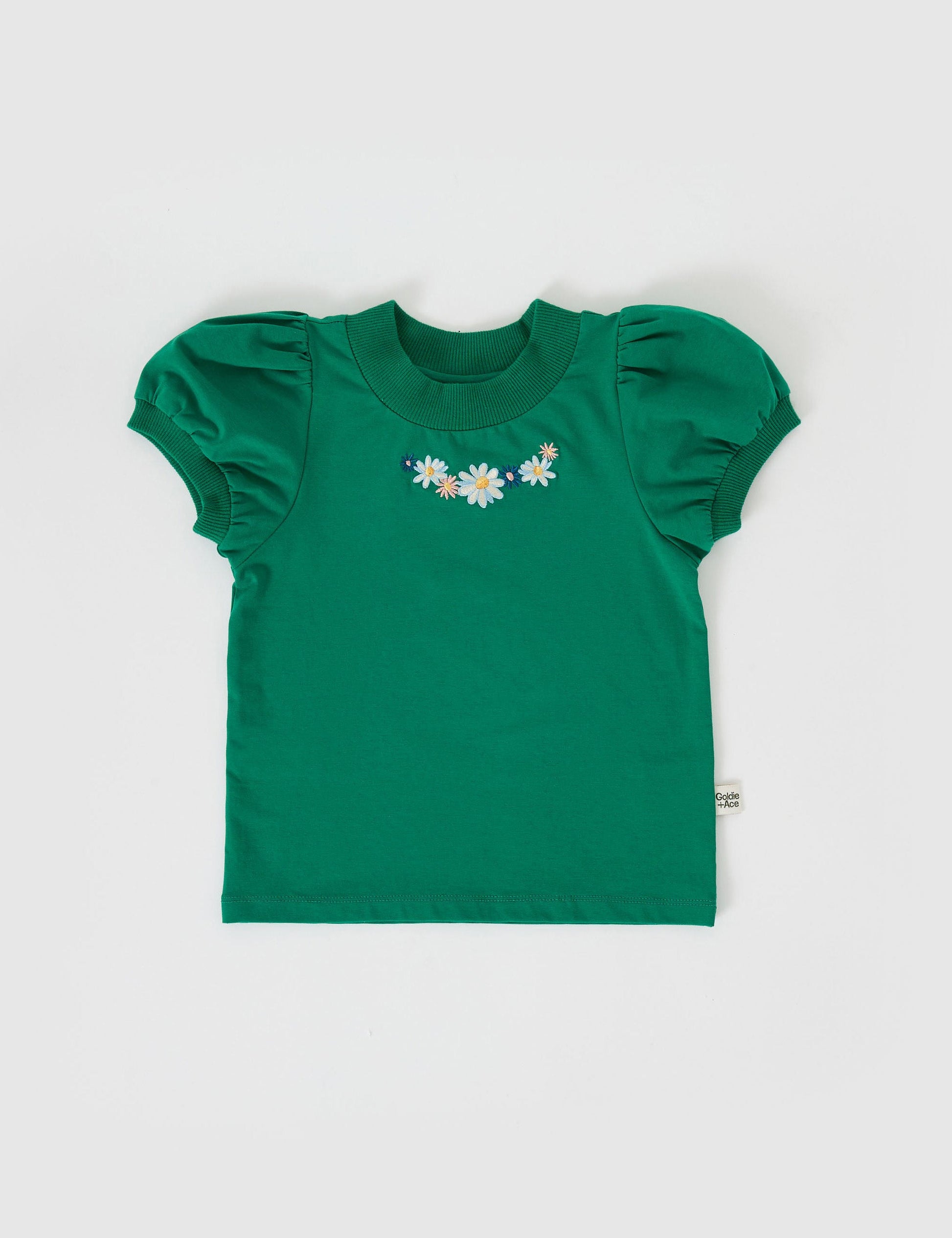 The Goldie + Ace Eden Embroidered Puff Sleeve T-Shirt in Bottle Green pictured on a grey background. The material is cotton jersey. It is a top made for babies, toddlers and kids.