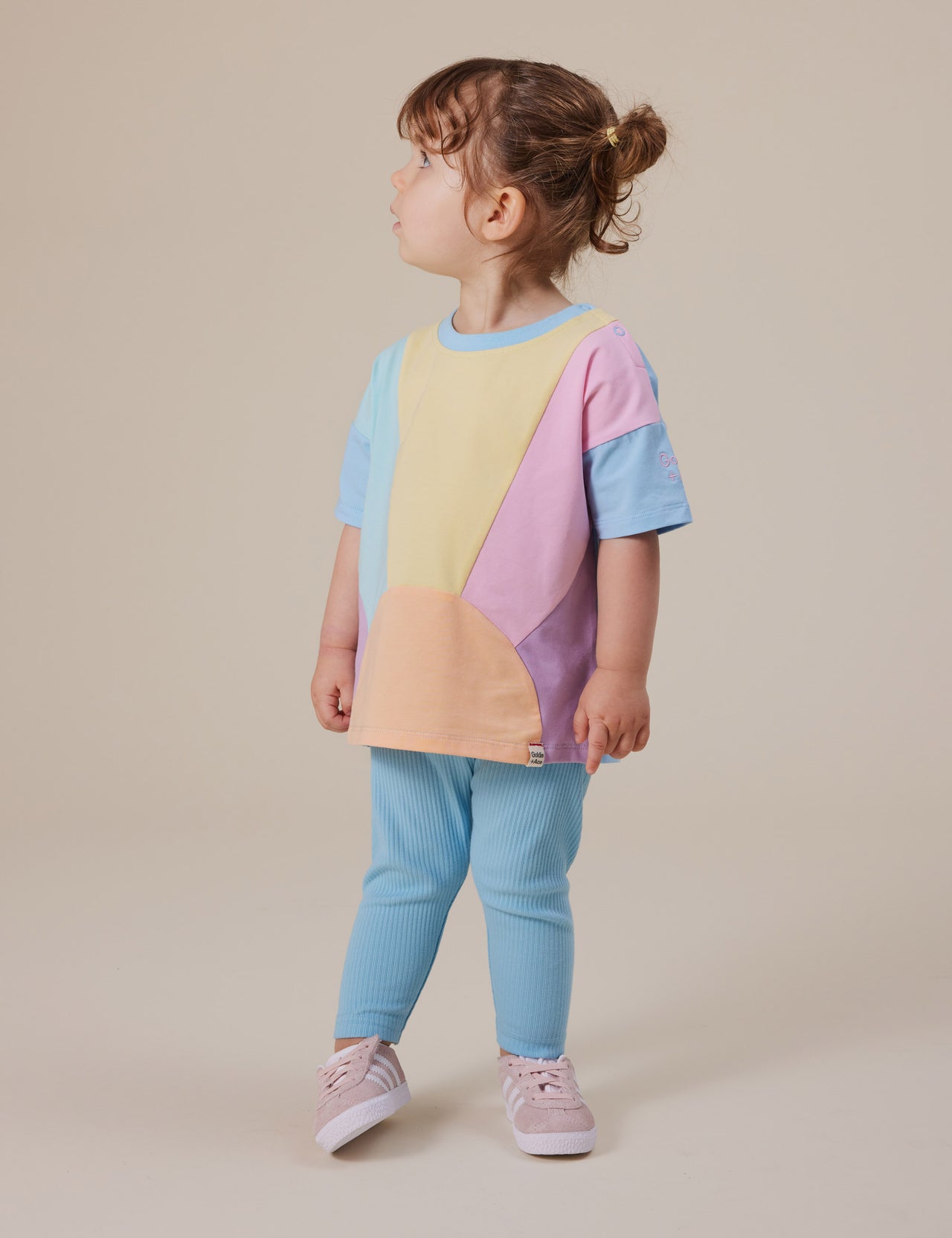 The Goldie + Ace Byron T-Shirt in Pastel Multi pictured on a grey background. The material is cotton jersey. It is a top made for babies, toddlers and kids.