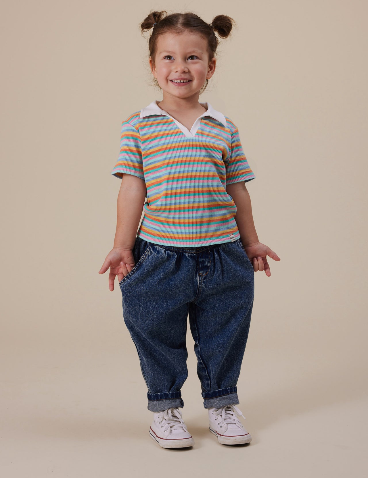 The Goldie + Ace Pia Collared T-Shirt in Candy Stripe pictured on a grey background. The material is soft ribbed cotton elastane. It is a top made for babies, toddlers and kids.