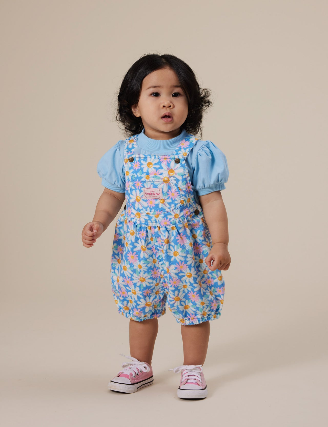 The Goldie + Ace Seaside Daisy Bessie Bubble Shortalls in Seaside Daisy pictured on a grey background. The material is cotton twill. It is a overall made for babies, toddlers and kids.