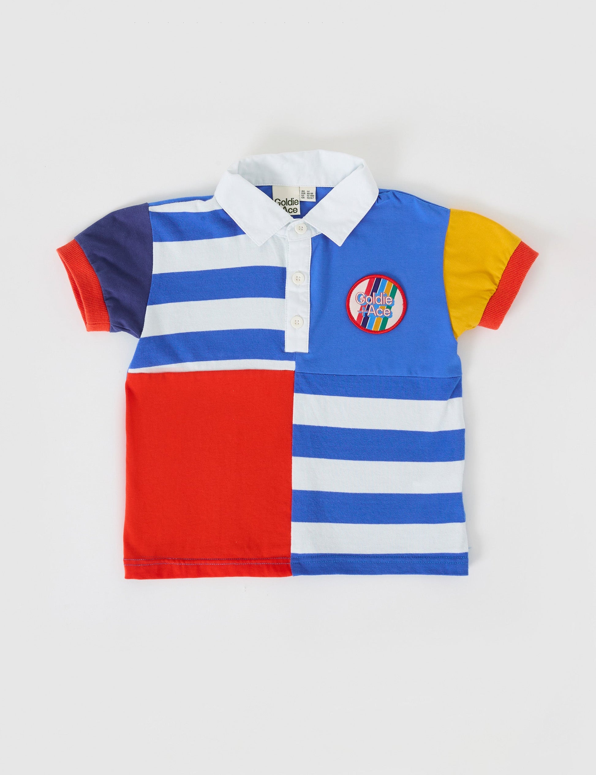 The Goldie + Ace Myles Colour Block Polo Shirt in Primary Multi pictured on a grey background. The material is cotton jersey. It is a top made for babies, toddlers and kids.