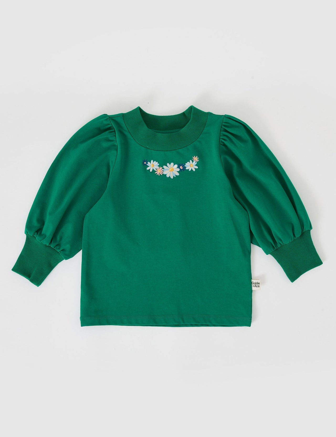 The Goldie + Ace Eden Embroidered Puff Sleeve Top in Bottle Green pictured on a grey background. The material is cotton jersey. It is a top made for babies, toddlers and kids.