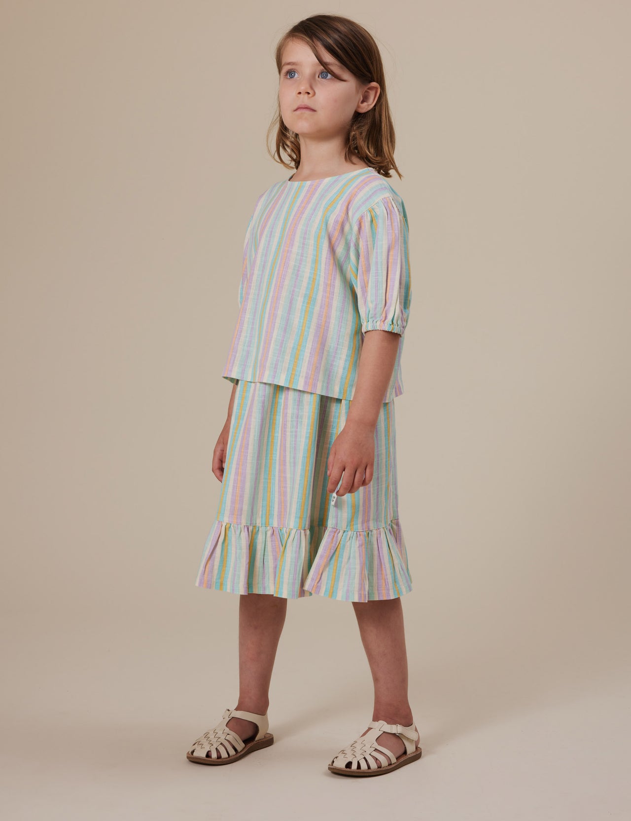 The Goldie + Ace Puff Sleeve Linen Top in Resort Stripe pictured on a grey background. The material is linen. It is a top made for babies, toddlers and kids.