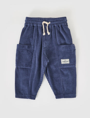 The Goldie + Ace Kit Corduroy Pocket Pant in Navy pictured on a grey background. The material is cotton cord. It is a bottom made for babies, toddlers and kids.