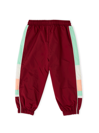 The Goldie + Ace Retro Sporty Pants in Brick/Peapod pictured on a transparent background. The material is poly with cotton lining. It is a bottom made for babies, toddlers and kids.