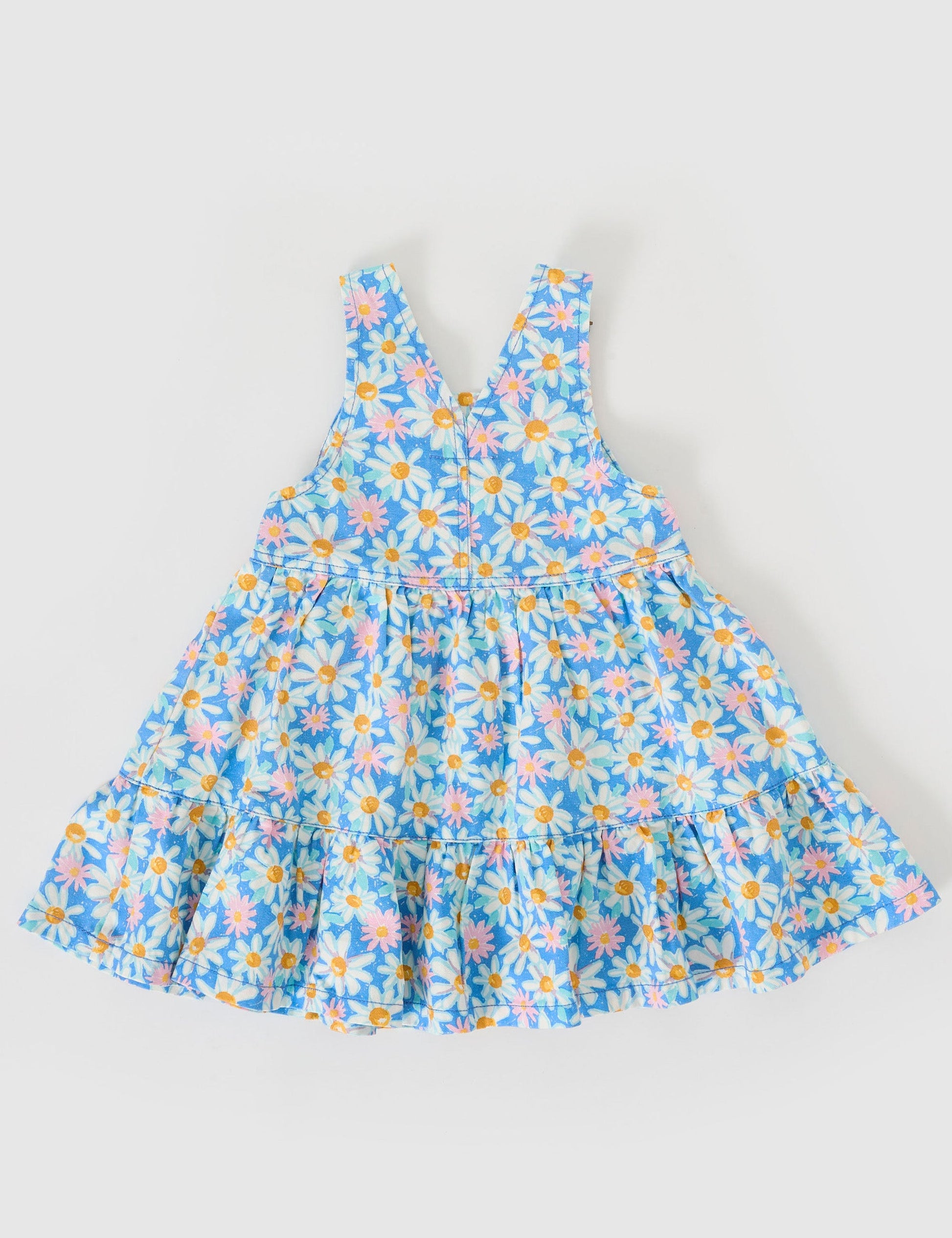 The Goldie + Ace Tully Tiered Pinafore Dress in Seaside Daisy pictured on a grey background. The material is cotton terry. It is a dress made for babies, toddlers and kids.