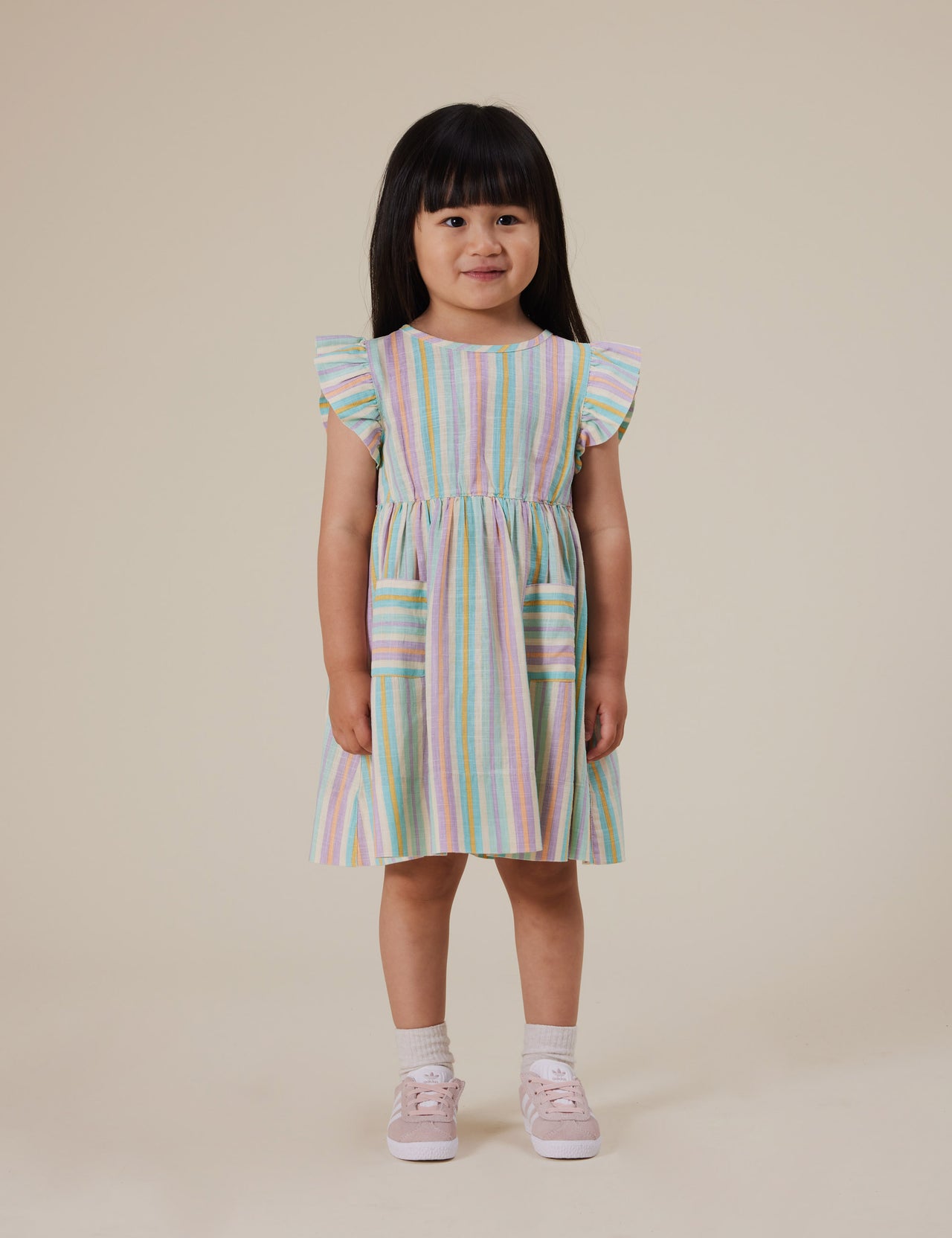 The Goldie + Ace Lyla Linen Dress in Resort Stripe pictured on a grey background. The material is linen. It is a dress made for babies, toddlers and kids.