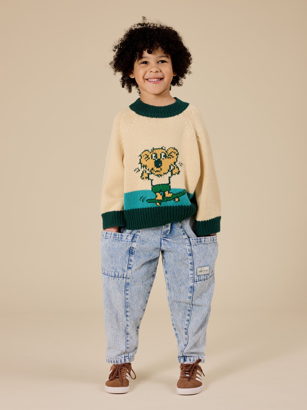 The Goldie + Ace Marley Koala Knit Jumper in Vanilla/Teal pictured on a transparent background. The material is soft acrylic blend with wool and nylon. It is a top made for babies, toddlers and kids.