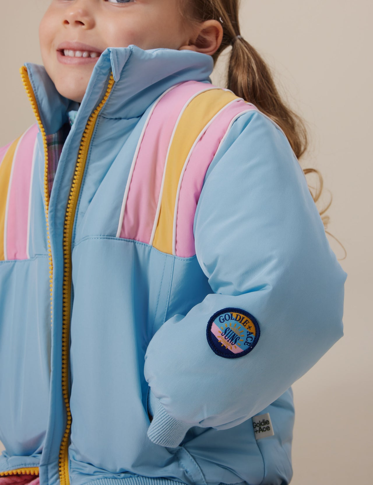 The Goldie + Ace Jordan Jacket in Sky Blue/Pink pictured on a grey background. The material is poly with poly lining. It is a jacket made for babies, toddlers and kids.