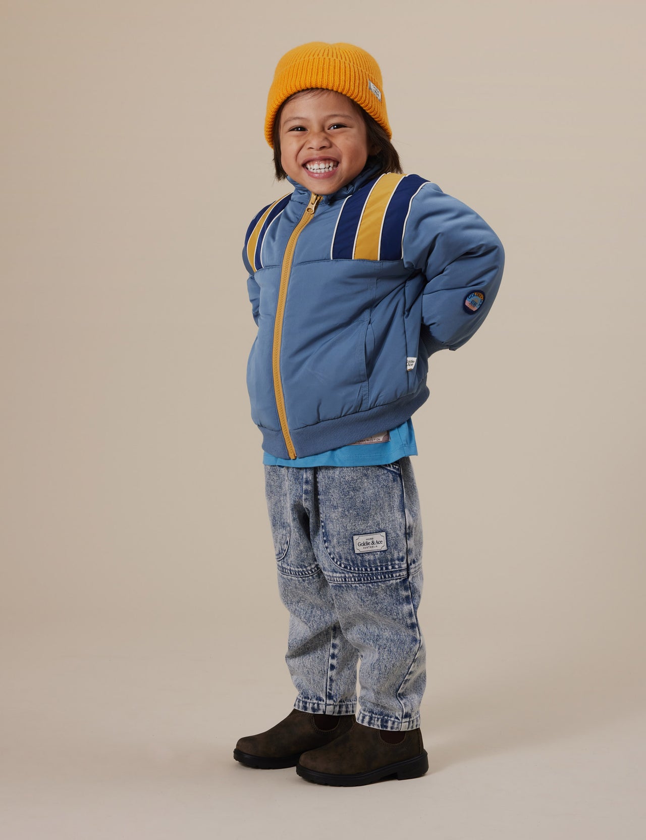 The Goldie + Ace Drew Denim Pocket Pant in Light Denim pictured on a grey background. The material is cotton denim. It is a bottom made for babies, toddlers and kids.