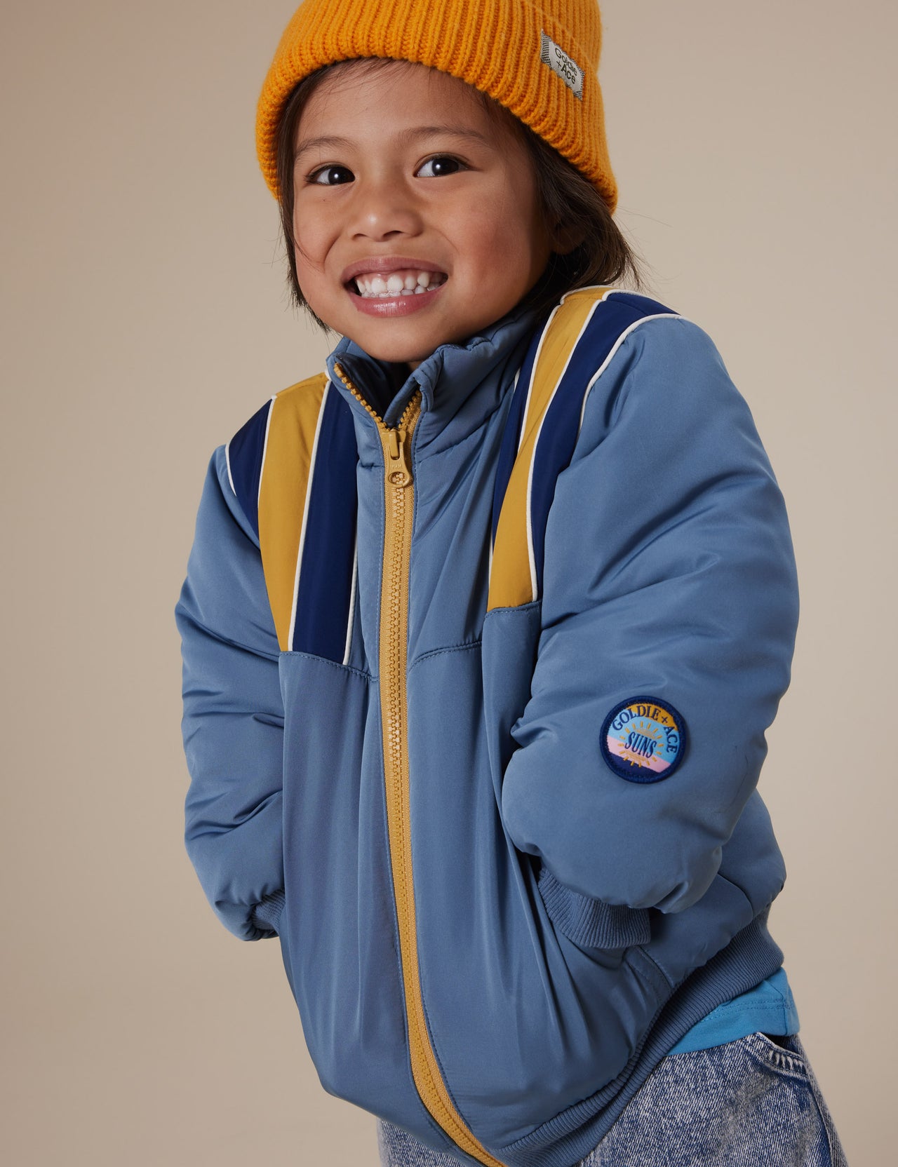 The Goldie + Ace Jordan Jacket in Duck Egg/Golden pictured on a grey background. The material is poly with poly lining. It is a jacket made for babies, toddlers and kids.